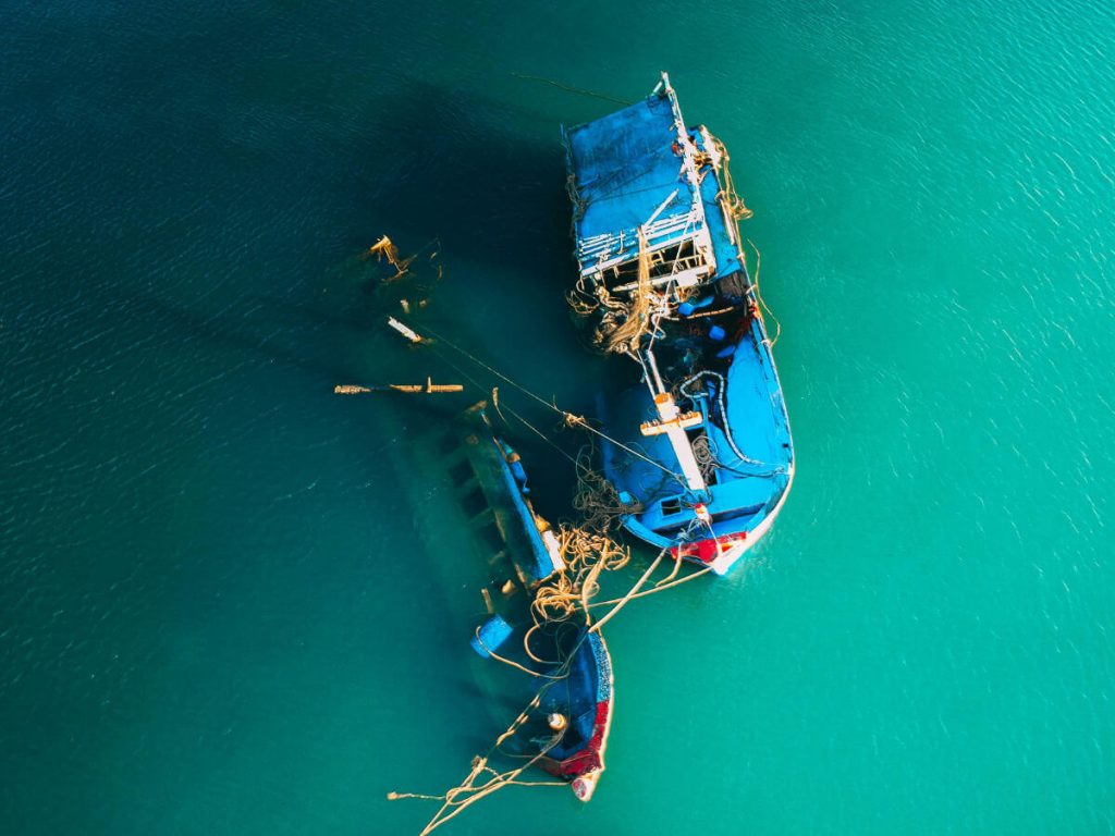 Two blue fishing boats in sinking into teal water