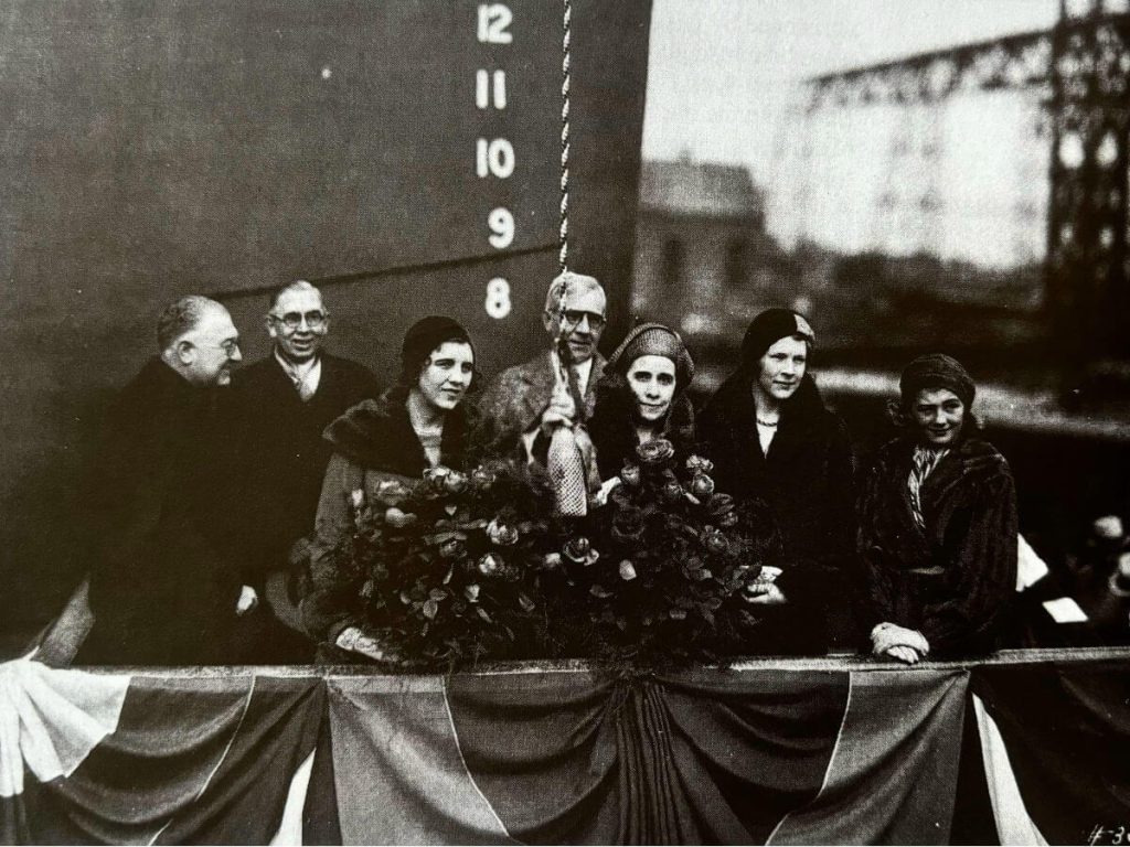 Mrs Grace Coolidge christening the S.S. President Coolidge with a bottle of river water on a rope