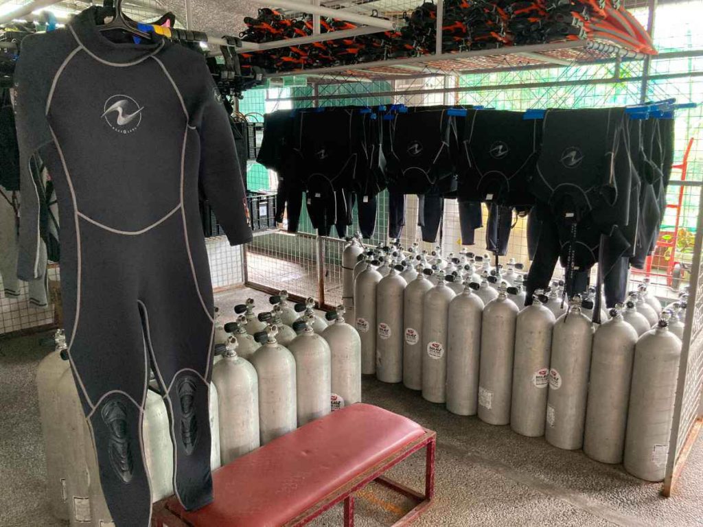 A Black aqualung wetsuit with full arms and legs hanging in a diving equipment room