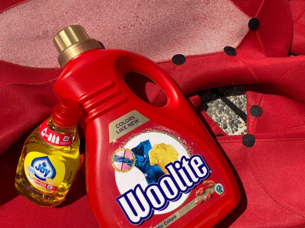 Yellow washing up liquid and woolite laundry detergent on top of a wetsuit