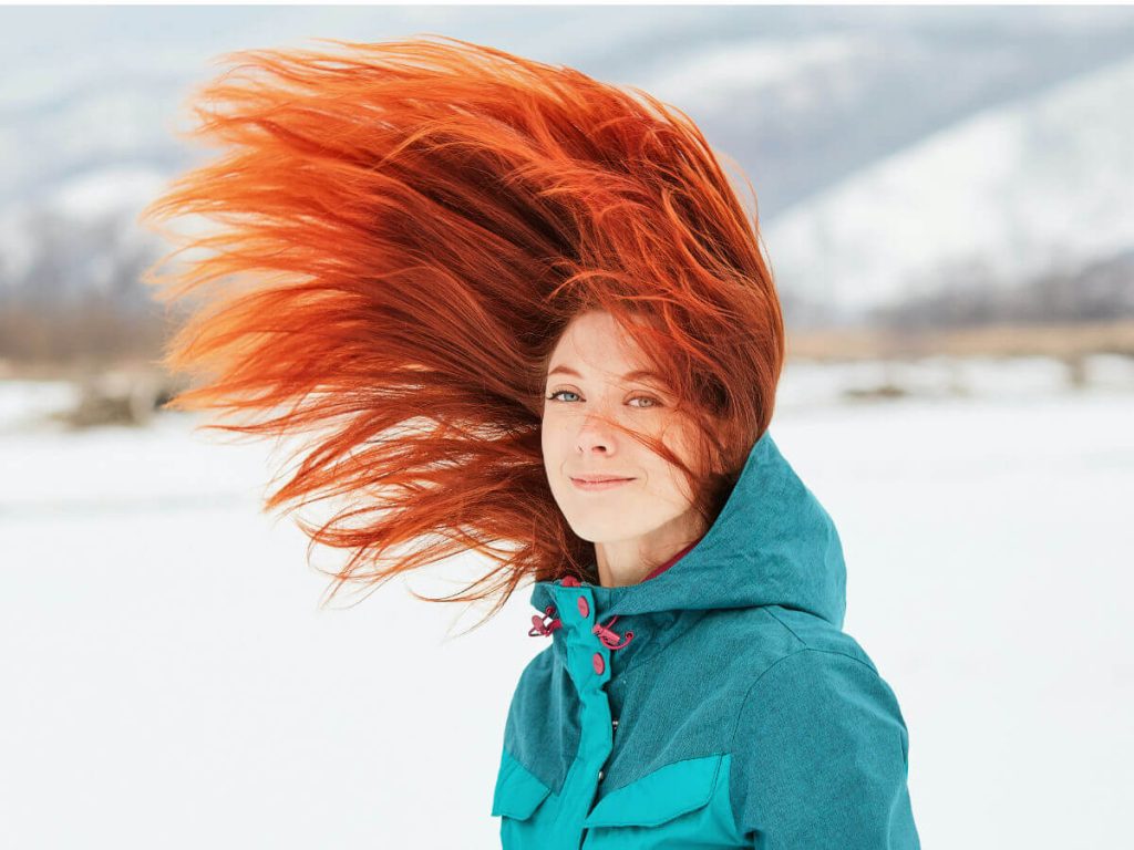 Woman with red hair throwing it up in the air and smiling