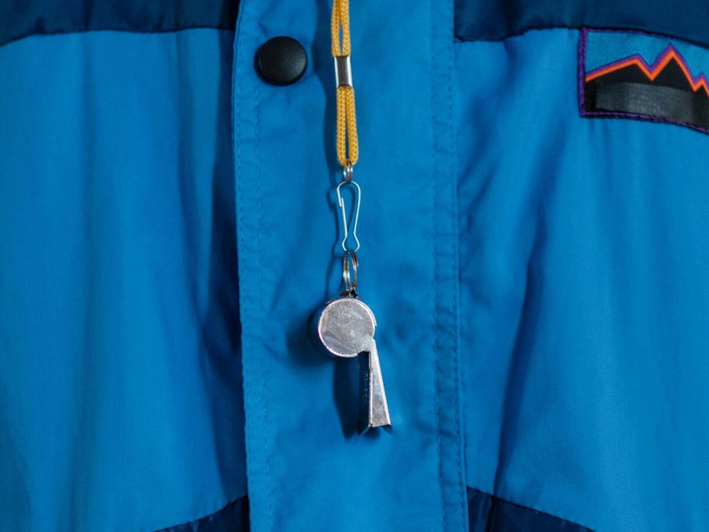 A close up of someone wearing a blue coat with a yellow whistle around their neck