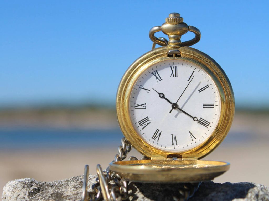 A Gold pocket watch on a rock on the beach