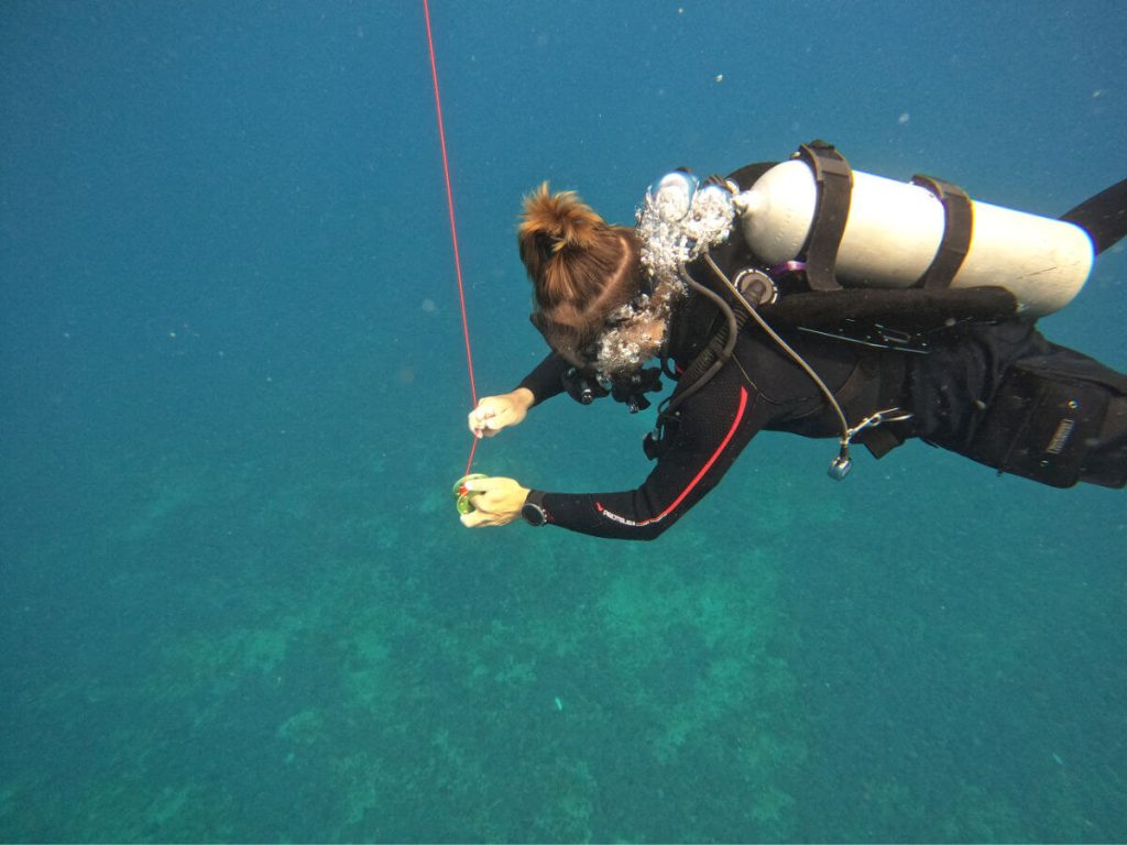 A Man scuba diving rolling in a orange spool