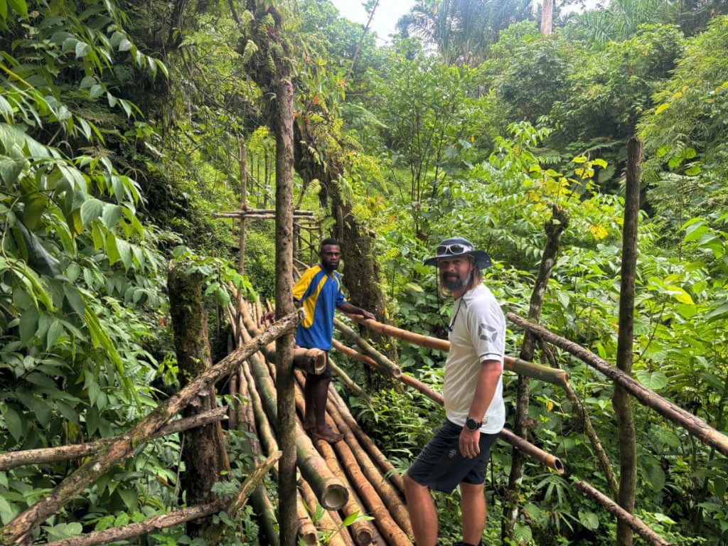 Two men crossing a bamboo bridge on the way to Millenium Cave