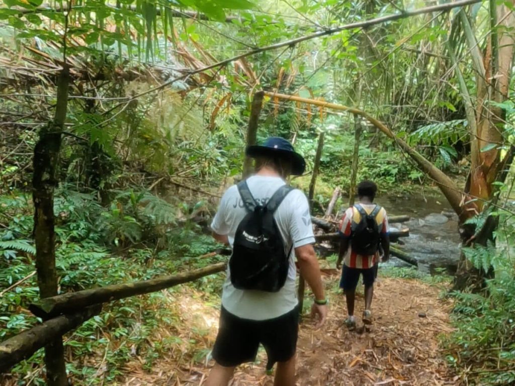 Two men hiking through mud in the jungle of Espiritu Santo