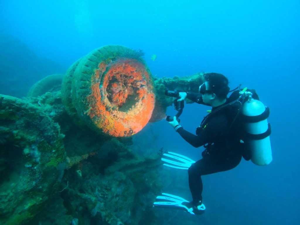 Scuba diver taking a picture of vehicle tires on Million Dollar Point, Espiritu Santo, Vanuatu