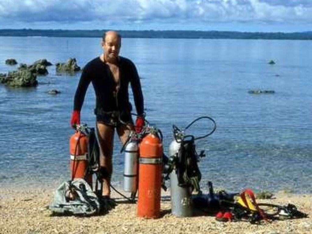 Allan Power with tanks on the beach in front of the SS President Coolidge dive site