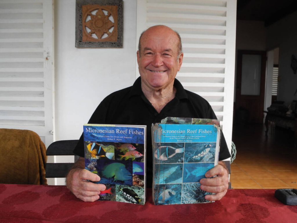Allan Power holding up books about marine life in Micronesia