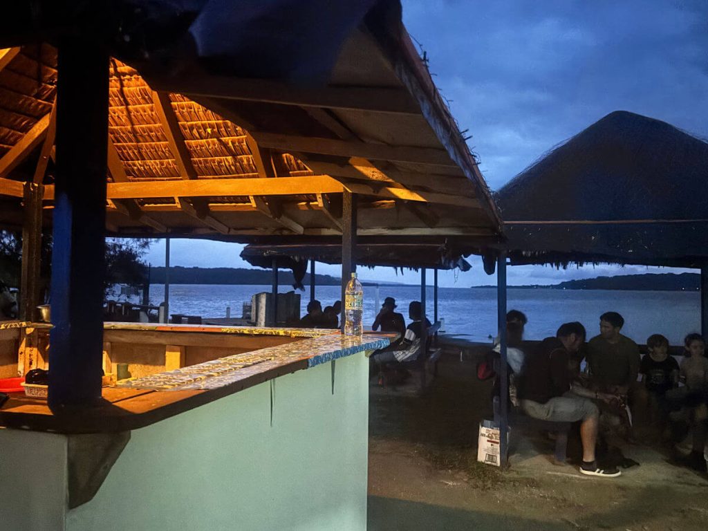 People sitting in a waterfront nakamal talking and experiencing kava culture